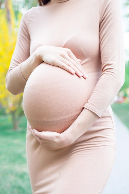 Młoda kobieta w ciąży, stojąc na zewnątrz w parku miejskim i trzymając jej brzuch macierzyństwo ciąży ludzi i koncepcja oczekiwania