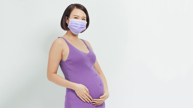 Młoda Kobieta W Ciąży Stojąca I Dotykająca Brzucha Nosząca Koncepcję Maski Chroniącej Przed Wirusami W Ustach