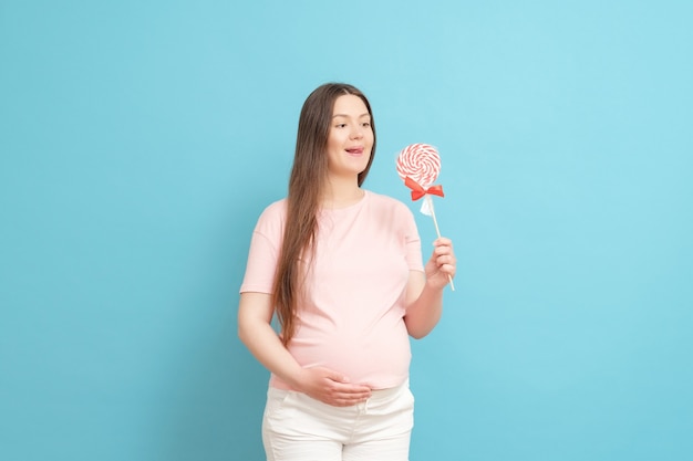 Młoda kobieta w ciąży z cukierkami w ręku