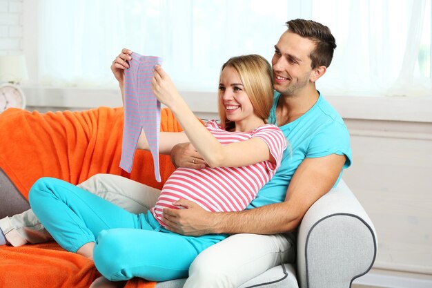 Młoda kobieta w ciąży z mężem na kanapie w pokoju