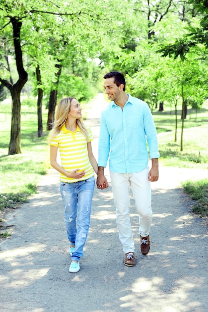 Młoda kobieta w ciąży z mężem spacerująca w parku
