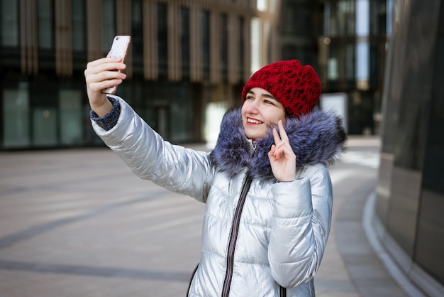 młoda kobieta w ciepłej kurtce rozmawia przez telefon na ulicy