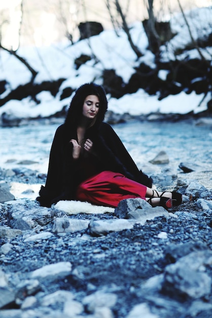 Zdjęcie młoda kobieta w ciepłych ubraniach siedząca na skałach