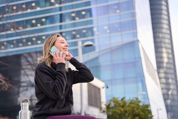 młoda kobieta w codziennych ubraniach rozmawia przez telefon w mieście