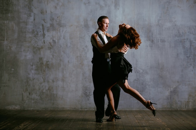 Młoda kobieta w czarnej sukni i mężczyzna tańczy tango