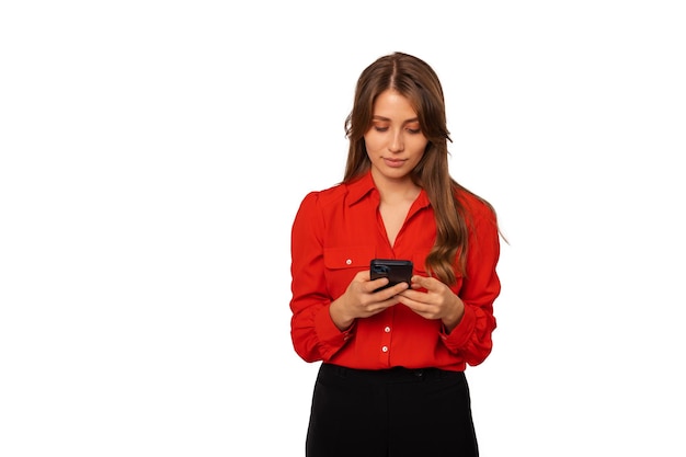 Młoda kobieta w czerwonej koszuli pisze na telefonie lub przegląda internet
