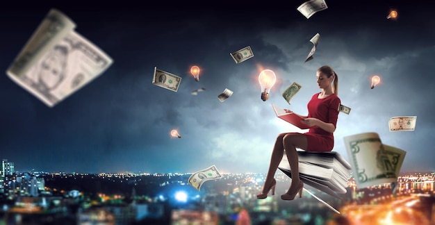 Młoda kobieta w czerwonej sukience czyta książkę z banknotów dolara latających wokół. Różne środki przekazu