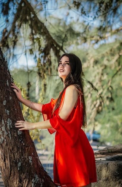 młoda kobieta w czerwonej sukience w lesie cieszącym się przyrodą