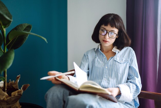 Młoda kobieta w domu pisania i pracy z notebookiem. Freelancer pracuje i robi notatki.