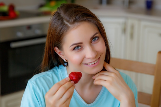 Zdjęcie młoda kobieta w domu w kuchni, jedzenie owoców
