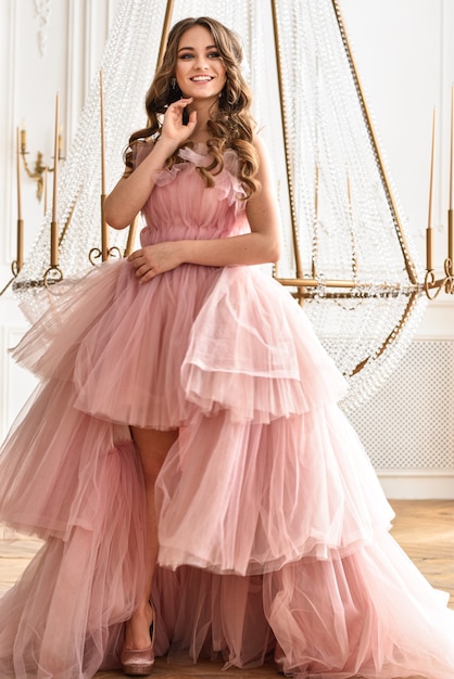 Młoda kobieta w eleganckiej puszystej różowej sukience.