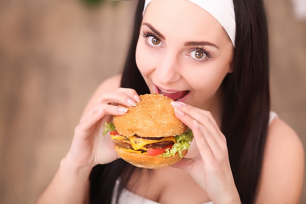 Młoda kobieta w eleganckiej restauracji je hamburgera, zachowuje się niewłaściwie