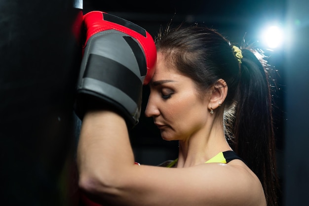 Młoda kobieta w jasnym dresie odpoczywa po treningu bokserskim