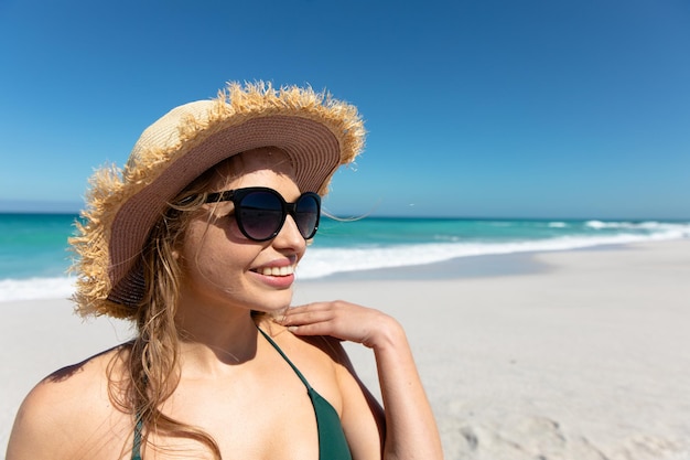 Młoda kobieta w kapeluszu uśmiecha się na plaży