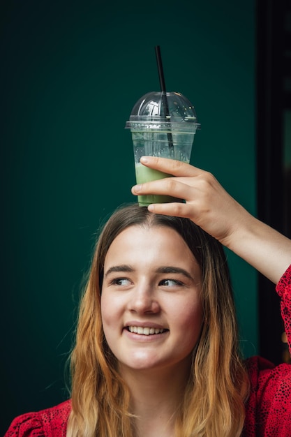 Młoda kobieta w kawiarni pije zielony napój ice latte