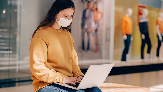 Młoda Kobieta W Masce Ochronnej Korzystająca Z Laptopa Na Ulicy Miasta