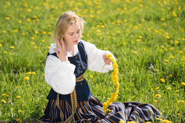 Młoda Kobieta W Narodowych Strojach Nosząca żółty Wieniec Z Mniszka Lekarskiego W Wiosennym Polu Wiosna
