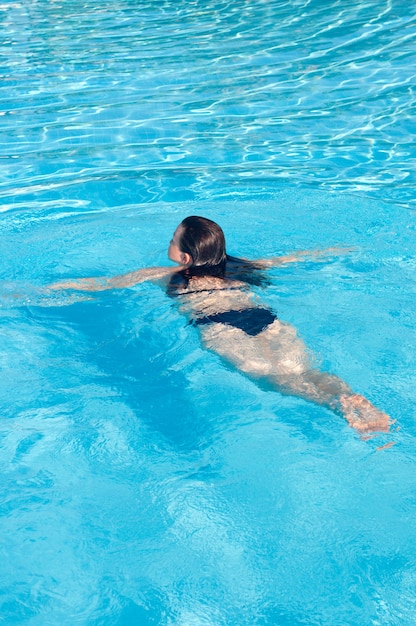 Młoda kobieta w niebieskim basenie wody