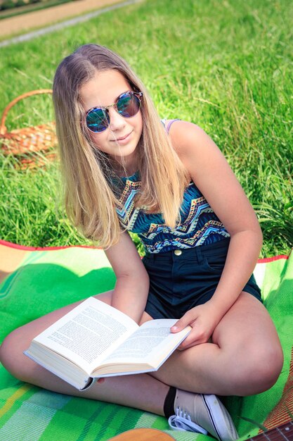 Zdjęcie młoda kobieta w okularach przeciwsłonecznych siedząca na książce
