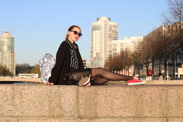 Zdjęcie młoda kobieta w okularach przeciwsłonecznych siedzi na moście