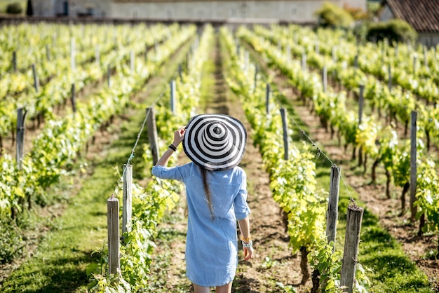 Młoda kobieta w pasiastym kapeluszu, podziwiając piękny zachód słońca na winnicy w regionie Bordeaux we Francji