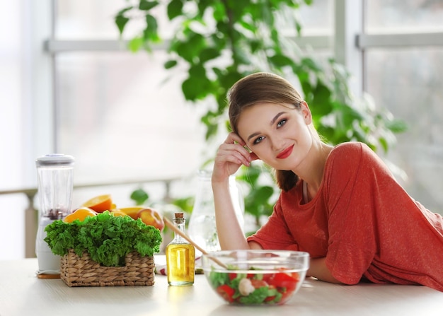 Młoda kobieta w pobliżu stołu z owocami i warzywami w kuchni