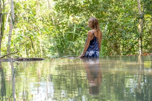 Młoda kobieta w pobliżu turkusowej wody kaskadowego wodospadu w głębokim tropikalnym lesie deszczowym, wyspa Koh Phangan, Tajlandia
