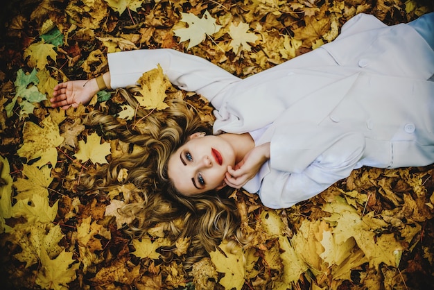 Młoda kobieta w pozycji leżącej na żółtych liściach