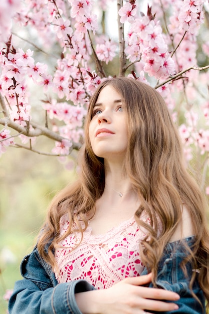 Młoda kobieta w różowym kwitnącym drzewie