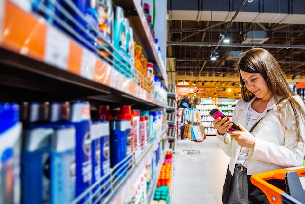 Młoda kobieta w sklepie z wózkiem wybiera szampon w supermarkecie na zakupy koncepcji przestrzeni kopii