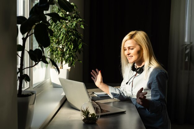 Zdjęcie młoda kobieta w słuchawkach pracuje na laptopie w biurze kobieta ze słuchawkami laptop