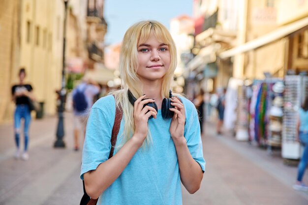 Młoda kobieta w słuchawkach z plecakiem na ulicy turystycznego miasta