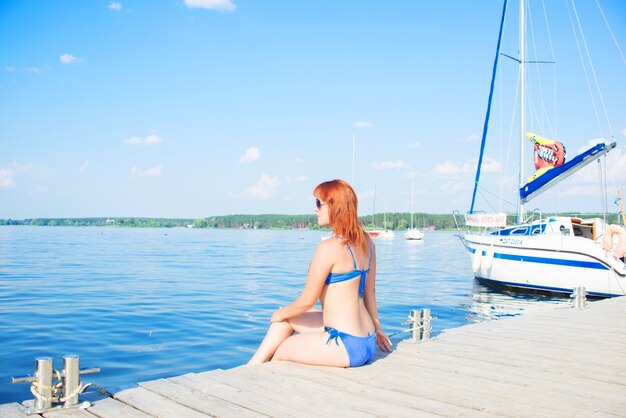 młoda kobieta w stroju kąpielowym siedzi w pobliżu morza