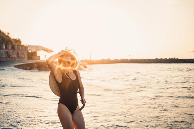 Młoda kobieta w stroju kąpielowym z piękną sylwetką na brzegu morza o zachodzie słońca Selektywne ustawianie ostrości