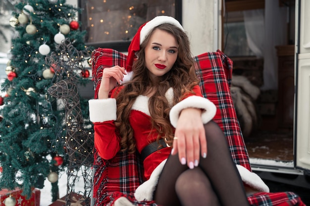 Młoda kobieta w stroju świętego mikołaja odpoczywa na zimowym kempingu koncepcja obchodów nowego roku