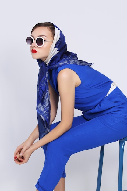 Młoda kobieta w stylu retro z okulary i jedwabny szal i niebieski kombinezon. Moda retro kobieta w stylu lat sześćdziesiątych.