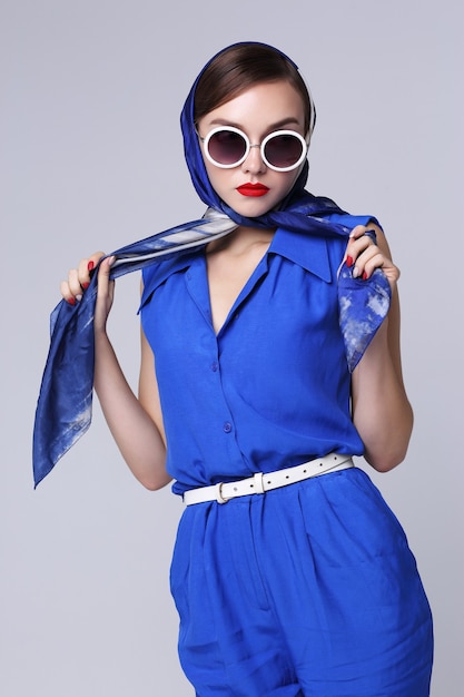 Młoda kobieta w stylu retro z okulary i jedwabny szal i niebieski kombinezon. Moda retro kobieta w stylu lat sześćdziesiątych.