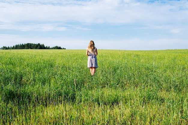 Młoda kobieta w sukni spaceru wzdłuż pola zbóż