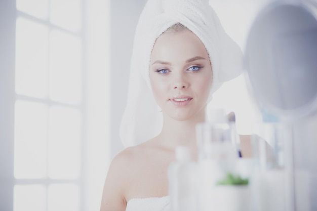 Młoda kobieta w szlafroku patrząca w lustro w łazience