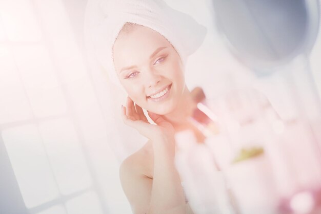 Młoda kobieta w szlafroku patrząca w lustro w łazience