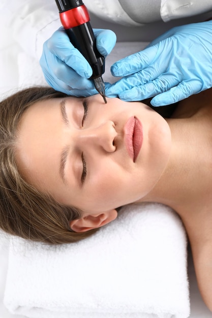 Młoda kobieta w trakcie procedury makijażu permanentnego w gabinecie kosmetycznym