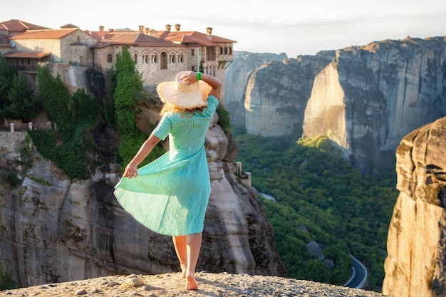 Młoda kobieta w zielonej sukience i kapeluszu ciesząca się przyrodą w górach w pobliżu klasztorów Meteory Grecja Meteory niesamowite formacje skalne z piaskowca Meteory znajdują się na liście UNESCO