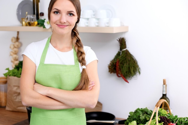 Młoda kobieta w zielonym fartuchu idzie gotować w kuchni Gospodyni domowa smakuje zupę drewnianą łyżką