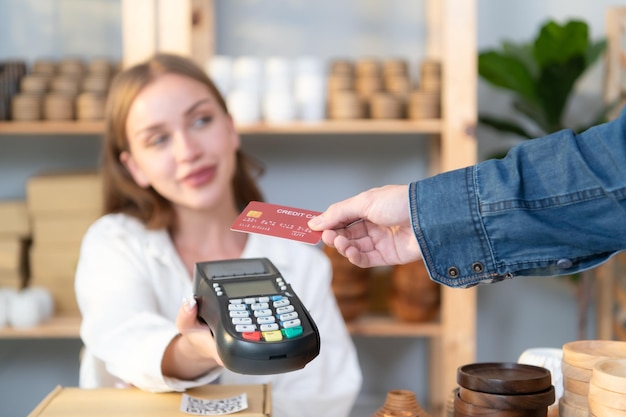 Młoda kobieta właścicielka małego przedsiębiorstwa z systemem płatności kartami kredytowymi