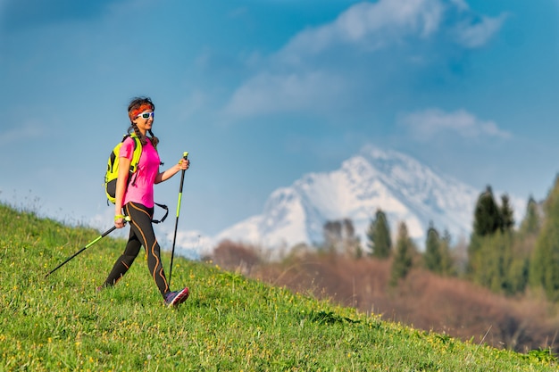 Młoda kobieta wraca z Nordic Walking na wycieczkę w góry wiosną