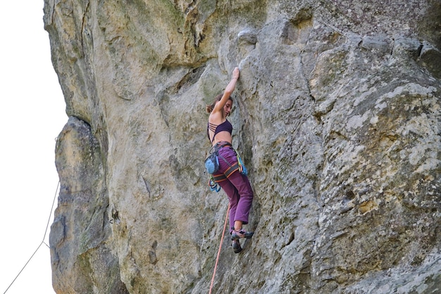 Zdjęcie młoda kobieta wspinaczki stromej ścianie skalistej góry. wspinaczka pokonuje trudną trasę. angażowanie się w koncepcję sportów ekstremalnych.