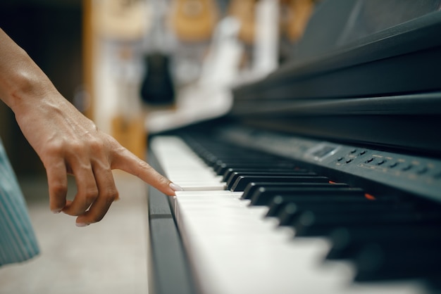 Młoda kobieta wybiera pianino cyfrowe w sklepie muzycznym