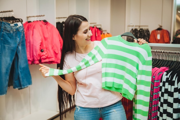Młoda kobieta wybiera ubrania w sklepie