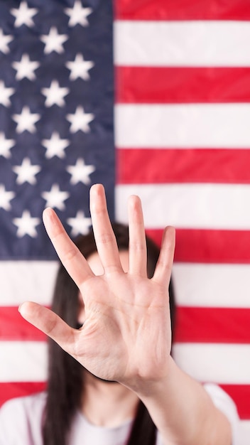 Młoda kobieta wyciąga dłoń do kamery i mówi stop aborcji Flaga amerykańska na tle z bliska