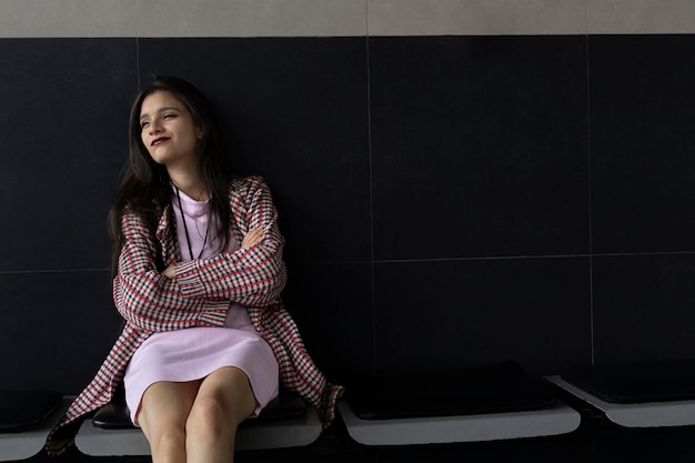 Młoda kobieta z Ameryki Łacińskiej, 22, siedząca w zrelaksowanej i oczekującej postawie Koncepcja młodości